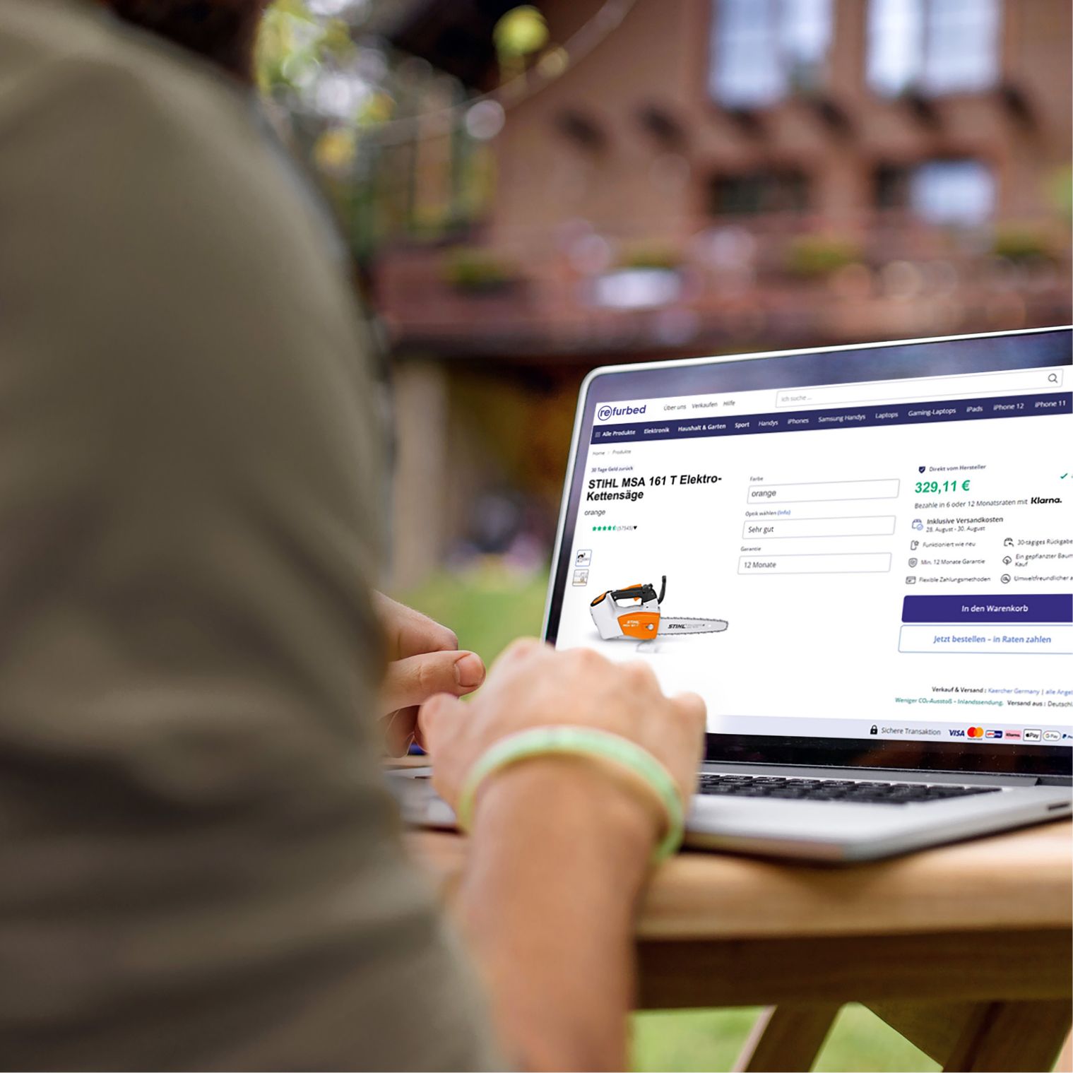 Person sitting in front of a laptop showing the Refurbed website.